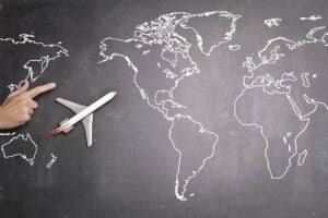 A hand holding a toy airplane flying over a map of the world.